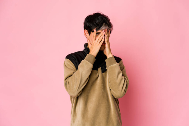 Young skinny hispanic man blink at the camera through fingers, embarrassed covering face. - 写真・画像