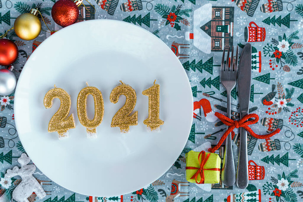 Xmas, winter, new year concept - layout white plate on which there are three Christmas trees cut from sausage cheese bread with santa hat and golden candles in form of numbers 2021 Blue background - Фото, зображення