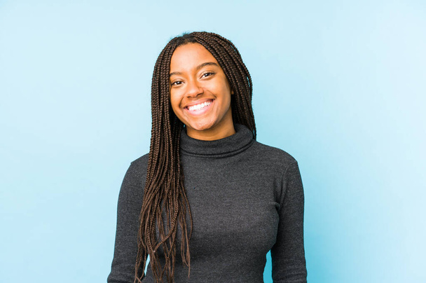 jonge afrikaanse amerikaanse vrouw geïsoleerd op blauwe achtergrond gelukkig, glimlachend en vrolijk. - Foto, afbeelding