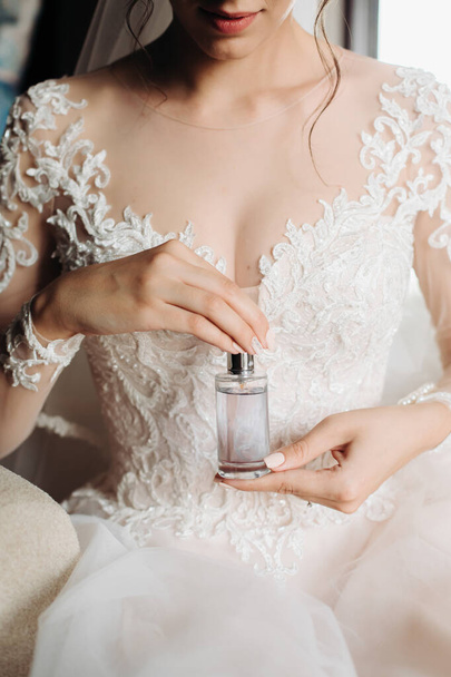 jar of perfume in the hands of the bride. Beautiful wedding manicure.Hands closeup. Wedding morning bride.white lace dress, beautiful neckline - 写真・画像
