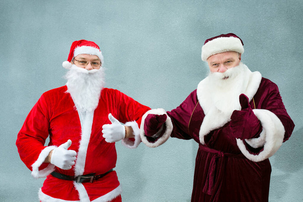 Rusya 'dan Ded Moroz ve Noel Baba tanıştı. Noel Baba 'nın ellerinde "Tamam" işareti var. Gri arkaplanda yakın plan. - Fotoğraf, Görsel
