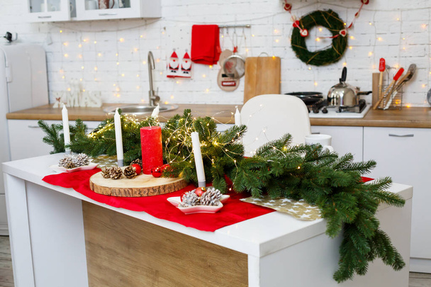 Πράσινο χριστουγεννιάτικο δέντρο, διακοσμημένο με μπάλες, χριστουγεννιάτικα στολίδια, κίτρινες γιρλάντες. Πρωτοχρονιάτικα στολίδια στην κουζίνα. Πρωτοχρονιά. Διακόσμηση στο σπίτι για τα Χριστούγεννα. - Φωτογραφία, εικόνα