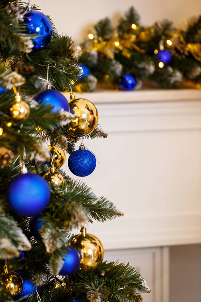 Zdobené vánoční stromeček zblízka. Modré a zlaté koule a věnec světla. Vánoční koule na stromě. Zimní dovolená Nový rok a Vánoce - Fotografie, Obrázek