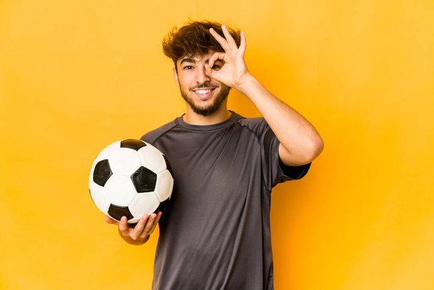 Joven jugador de fútbol indio hombre emocionado mantener el gesto bien en el ojo. - Foto, imagen