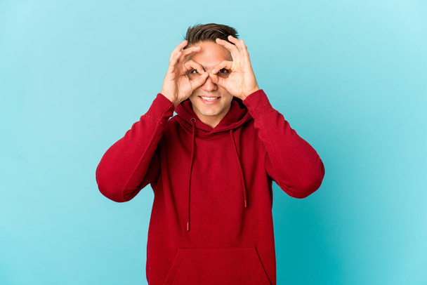 Young caucasian handsome man isolated showing okay sign over eyes - Foto, imagen