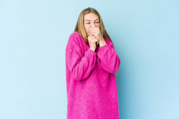 Nuori blondi nainen eristyksissä sinisellä taustalla kärsii kipua kurkussa viruksen tai infektion vuoksi. - Valokuva, kuva