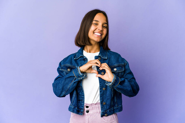 Young mixed race woman smiling and showing a heart shape with hands. - Photo, Image