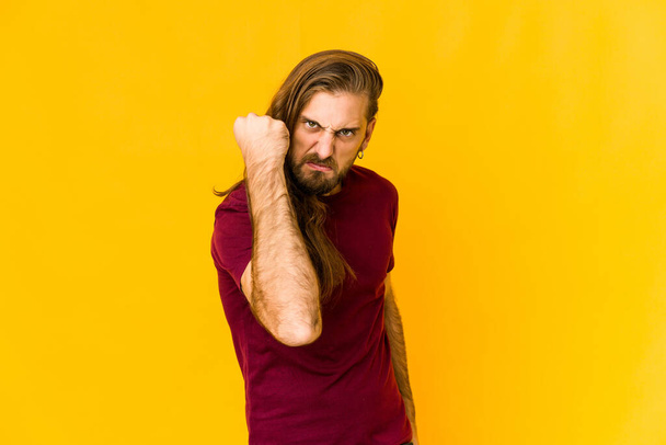 Young man with long hair look showing fist to camera, aggressive facial expression. - Photo, Image