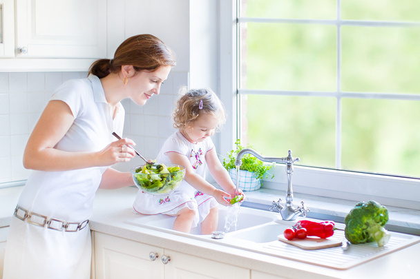 Äiti ja hänen tyttärensä pestä vihanneksia
 - Valokuva, kuva