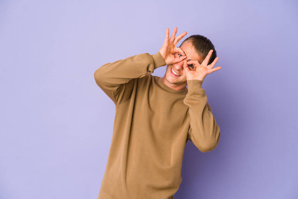 Young caucasian handsome man showing okay sign over eyes - Fotoğraf, Görsel