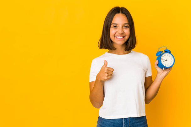 Junge hispanische Frau hält ein Megafon in der Hand, lächelt und hebt den Daumen - Foto, Bild