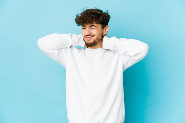 Young arab man on blue background suffering neck pain due to sedentary lifestyle. - Photo, Image