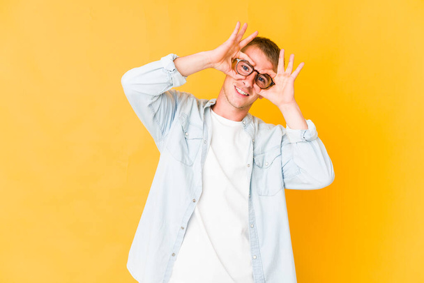 Young caucasian handsome man showing okay sign over eyes - Photo, Image