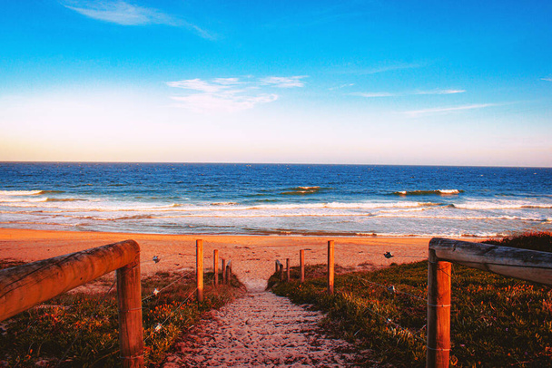 太陽の光と青空の下、海に囲まれたビーチの小さな階段 - 写真・画像