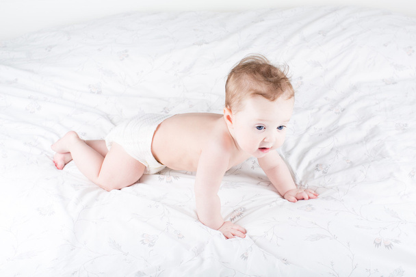 μωρό που μπουσουλάει στο ένα λευκό κρεβάτι - Φωτογραφία, εικόνα