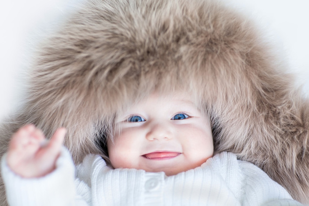 Baby girl with big blue eyes wearing a huge winter hat - Fotoğraf, Görsel