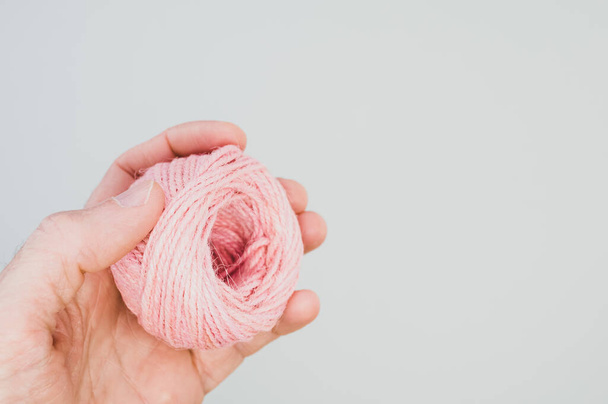 A closeup shot of a hand holding a pink yarn ball for knitting - Foto, afbeelding