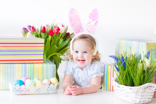 Pikkulapsi tyttö pupu korvat leikkii pääsiäisen lahjoja
 - Valokuva, kuva