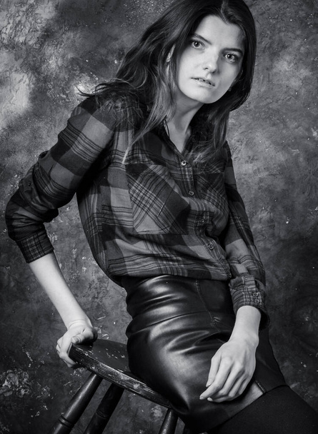 Studio portrait of young beautiful woman in a leather skirt - Фото, зображення