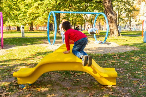 POZNAN, POLAND - Oct 13, 2018: Young child on a yellow plastic slide equipment at a playground - Foto, immagini