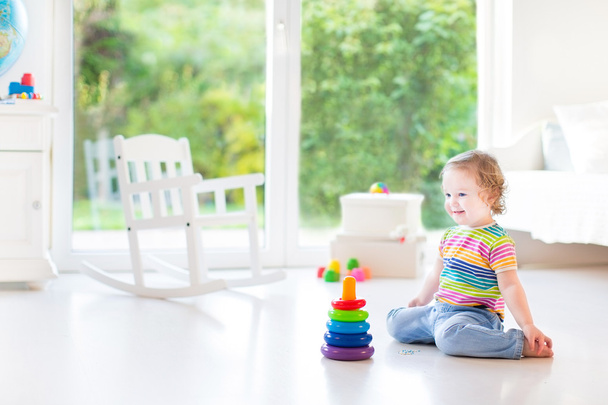 Toddler girl playing with a colorful pyramid - Foto, afbeelding