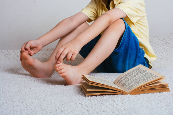 A closeup shot of a male child sitting next to an open book - Foto, Bild
