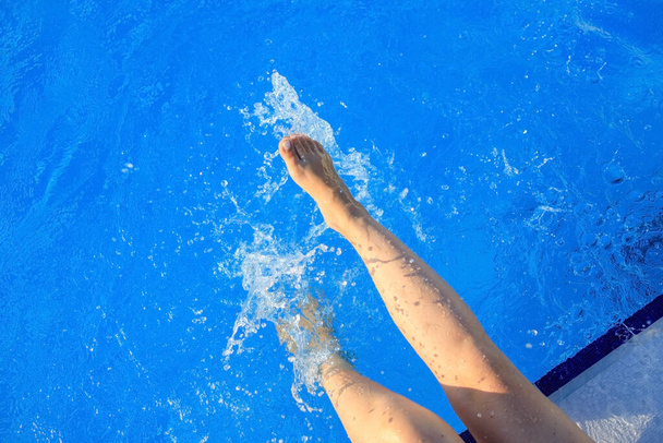 Kırpılmış genç Avrupalı kadın havuza tekme atıyor ve su sıçrıyor. Kavram, tasasız, yaz, tatil. Uzayı kopyala Yukarıdan görüntüle - Fotoğraf, Görsel