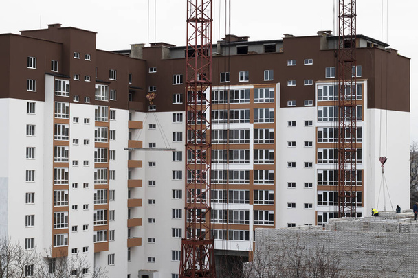 Κατασκευή με πολλούς ορόφους και μεγάλους μεταλλικούς γερανούς. Καινούρια κατασκευή σπιτιών και μεγάλοι γερανοί. Ουκρανία, Βίννιτσια - 1 Δεκεμβρίου 2020. - Φωτογραφία, εικόνα