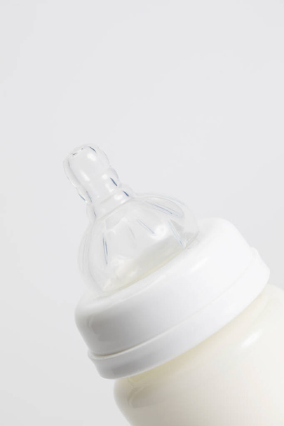 Egy függőleges felvétel egy tejjel teli cumisüvegről fehér háttérrel a másolóhelyért. - Fotó, kép