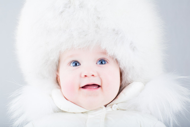 Funny laughing baby in a big white fur hat - Fotografie, Obrázek