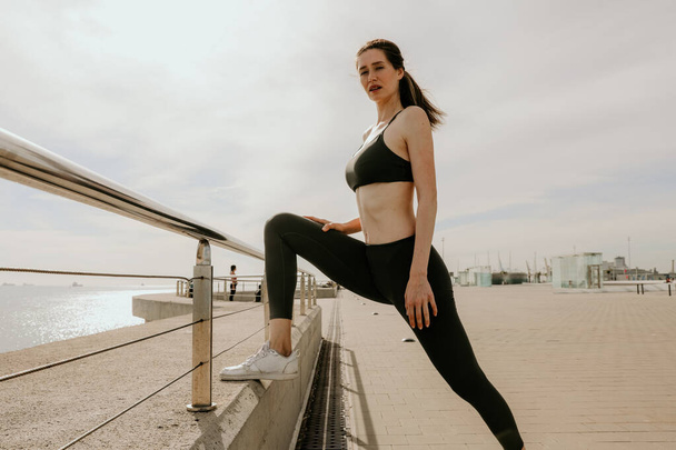 Sporty and happy woman stretching body after jogging, posing outdoor. - Фото, зображення