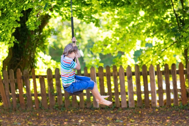 Funny little boy enjoying a swing ride - Fotoğraf, Görsel