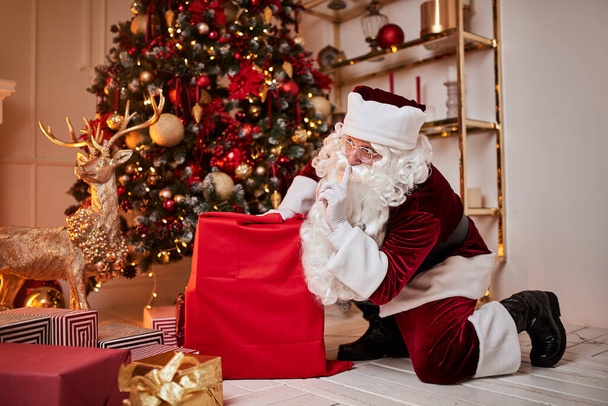 Der Weihnachtsmann mit einem großen roten Sack voller Geschenke eilt herbei, um den Kindern Geschenke zu bringen. Neues Jahr und frohe Weihnachten, frohe Feiertage - Foto, Bild