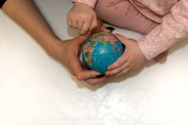  Hands of mother and child holding a globe - Foto, Imagen