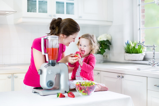 Irl y su joven madre haciendo jugo de fresa fresco
 - Foto, Imagen