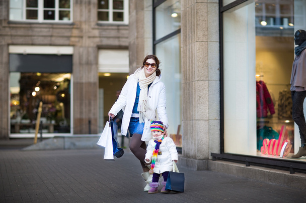 Woman and her toddler daughter enjoying winter sale shopping - Zdjęcie, obraz