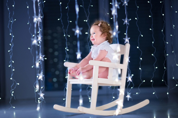 Toddler girl relaxing in a white rocking chair - Фото, изображение
