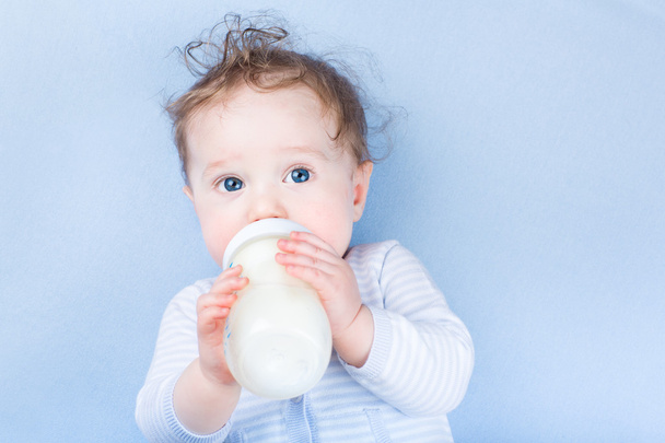 Petit bébé aux grands yeux bleus buvant du lait
 - Photo, image