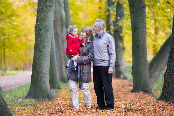 Família com uma menina caminhando juntos em um parque de outono
 - Foto, Imagem