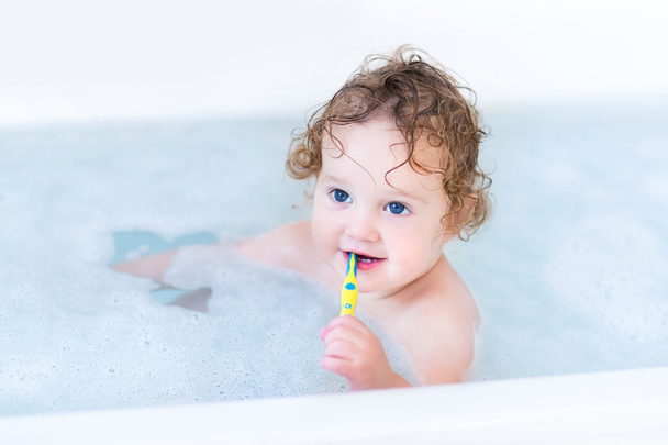 Bébé aux beaux yeux bleus et aux cheveux bouclés prenant son bain
 - Photo, image