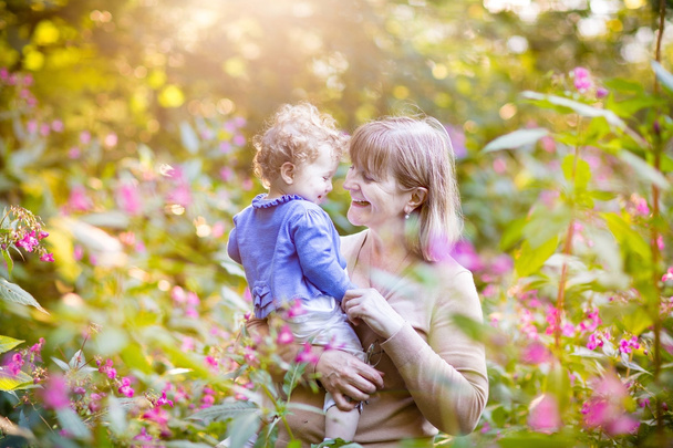 Mujer jugando con una niña feliz en un jardín
 - Foto, Imagen