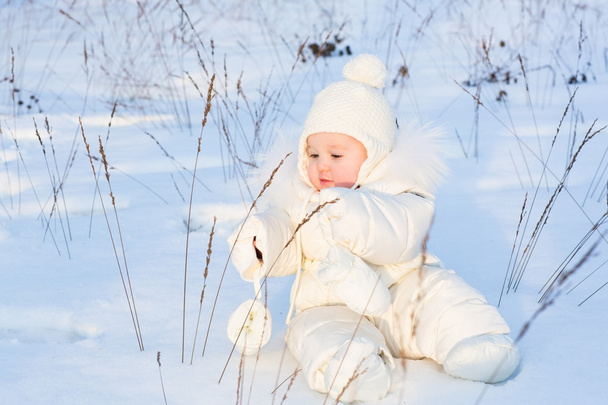 Bebé divertido jugando con hierba en un campo de nieve
 - Foto, imagen