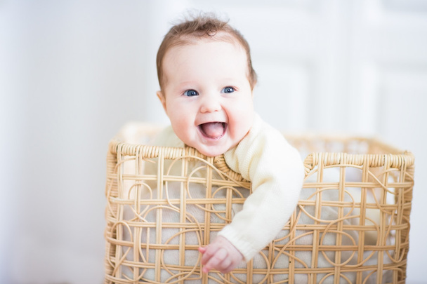 Bebé sentado en una cesta de lavandería
 - Foto, imagen