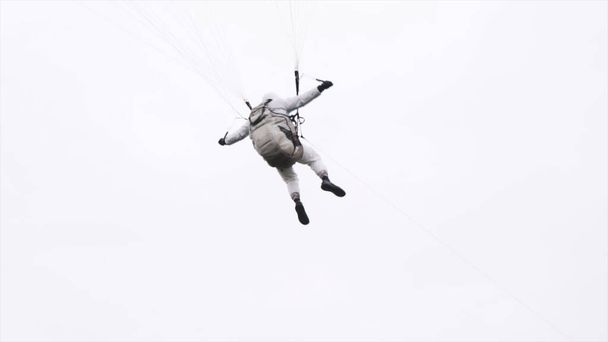  Vue impressionnante d'un parachutiste militaire volant en parachute d'aile coloré. L'action. Homme courageux et entraîné volant et tirant les élingues de parachute pour changer la direction de vol. - Photo, image