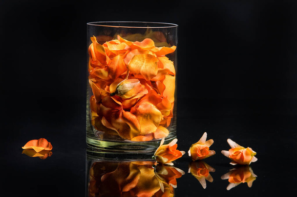 Flower petals in a glass on a black background - Foto, Bild