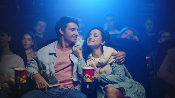 Glückliches Paar beim Kinobesuch. Glücklicher Mann küsst Frau in dunkler Halle. - Foto, Bild