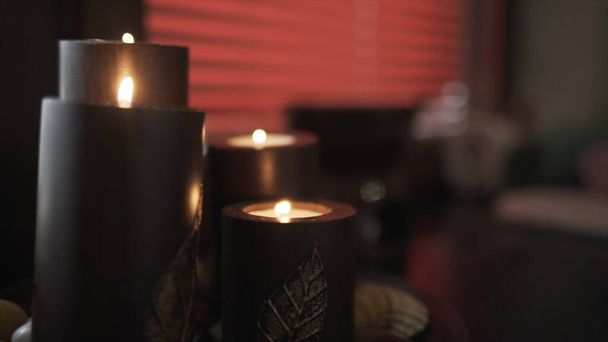 Primo piano di grandi candele scure che creano un'atmosfera romantica e calma. Azione. Dettagli e decorazioni di interni stanza, candele aroma di cioccolato sullo sfondo di tende rosse. - Foto, immagini