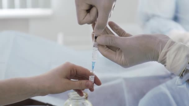 The doctor draws medicine into a syringe from an ampoule. Action. Close up of doctor hands in protective gloves preparing antiviral drug, vaccine against coronavirus covid 19.  - Footage, Video