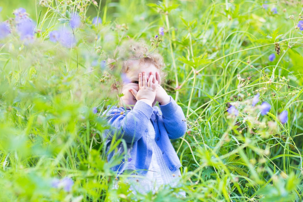 Chica jugando al escondite en el jardín
 - Foto, Imagen