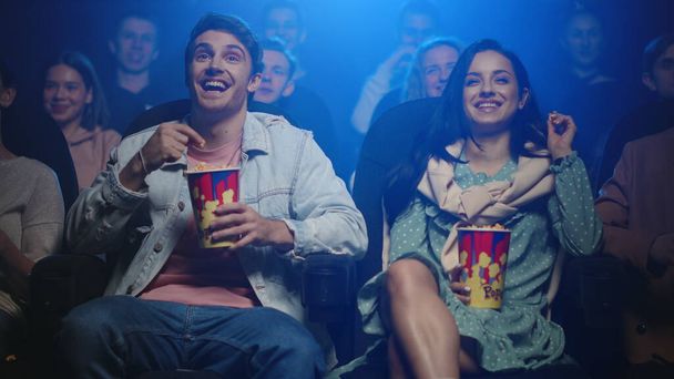 Χαρούμενο ζευγάρι που βλέπει ταινία σε εσωτερικούς χώρους. Ευτυχισμένοι φίλοι διασκεδάζουν στον κινηματογράφο. - Φωτογραφία, εικόνα